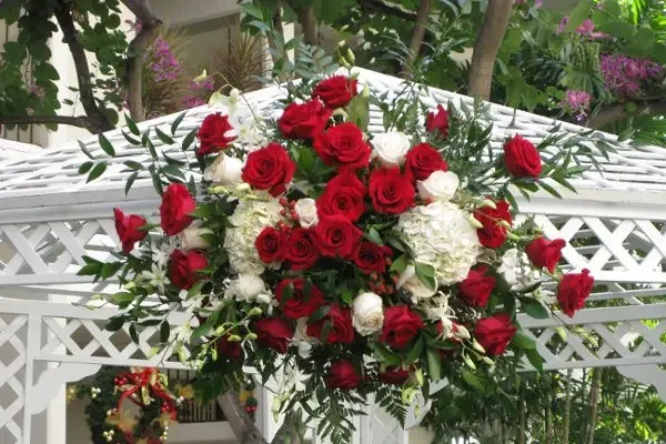 A large spray of red and white roses mounted on a white gazebo.